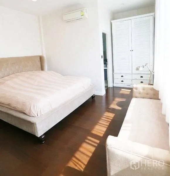 Detached House for rent or sale in Bang Kapi, Bangkok - Bright secondary bedroom with upholstered bed, wardrobe and wooden flooring.