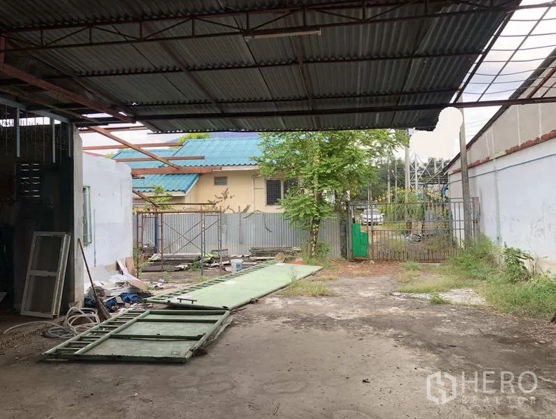 货栈 出租在Sai Mai, Bangkok - 院内带顶装卸区与宽阔空地，滑动大门部件置于地面。