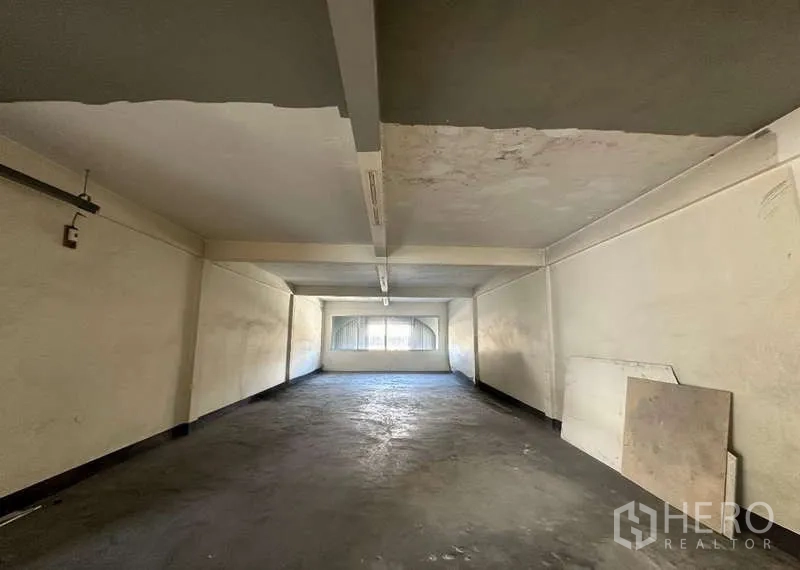 Office Space for rent in Phra Khanong, Bangkok - Long rectangular room with concrete floor, low ceiling beams and a rear window for natural light.