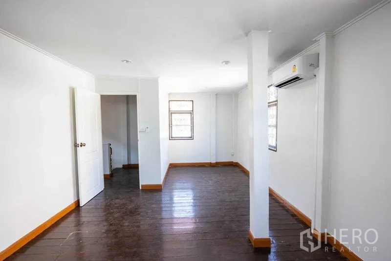 Home Office for rent in Watthana, Bangkok - Upper floor room with dark wood flooring, white walls, and wall-mounted air-conditioner.