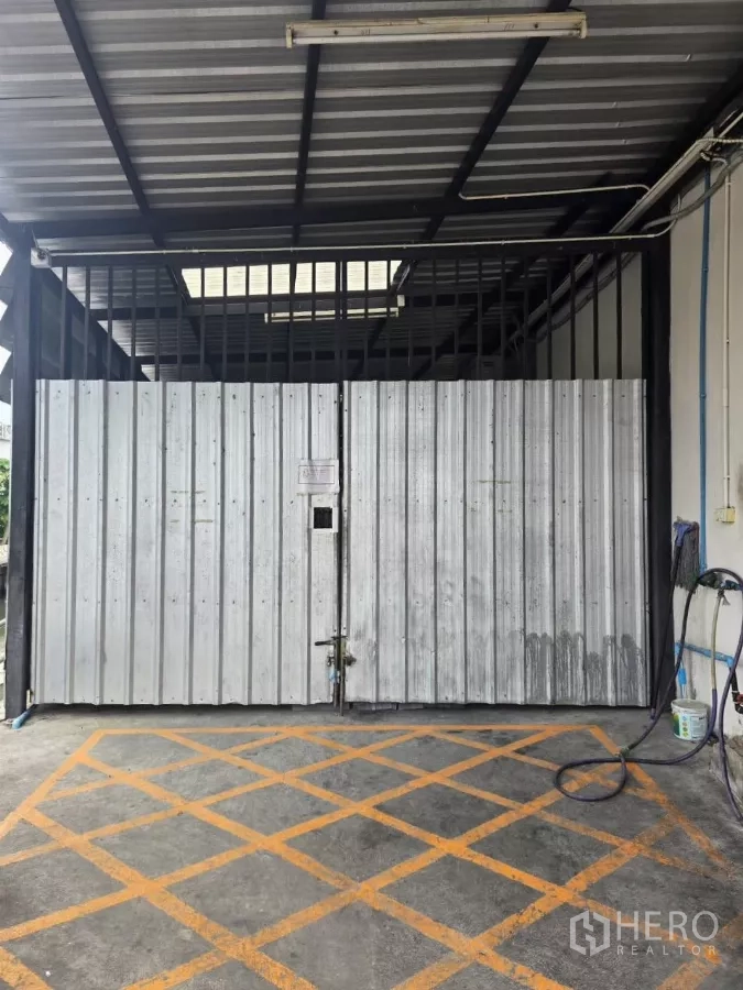 Warehouse for rent in Chatuchak, Bangkok - Large sliding metal gate at warehouse entrance with sheltered driveway.
