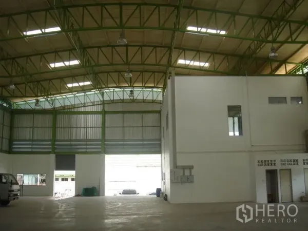 Warehouse for rent in Lat Krabang, Bangkok - High-bay warehouse interior with green steel trusses, skylights, large roller shutter access and an internal office block.