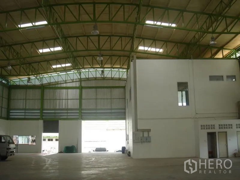 Warehouse for rent in Lat Krabang, Bangkok - High-bay warehouse interior with green steel trusses, skylights, large roller shutter access and an internal office block.