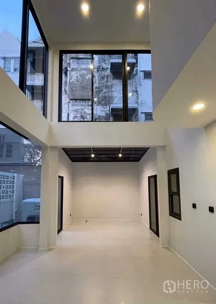 Home Office for sale in Lat Phrao, Bangkok - Double-height living area with floor-to-ceiling windows and a mezzanine.