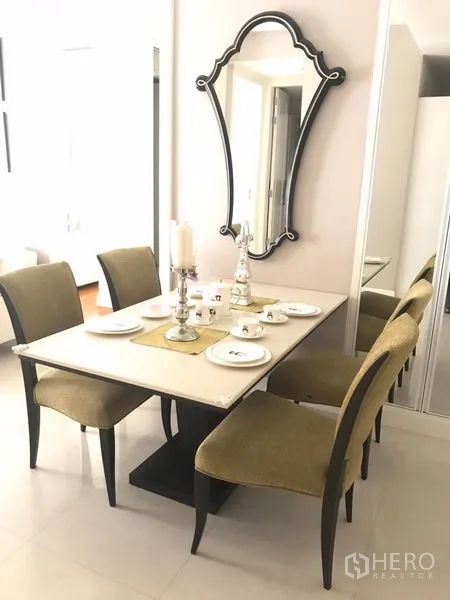 Condominium for rent in Pathum Wan, Bangkok - Dining nook with four upholstered chairs, rectangular table set for four and a stylish wall mirror.