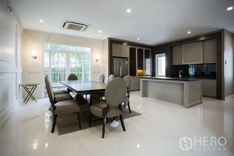 Detached House for rent in Mueang Samut Prakan, Samut Prakan - Open-plan dining area and modern island kitchen with built-in cabinetry and wide windows.