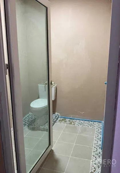 货栈 出租在Sai Noi, Nonthaburi - 简洁卫生间，玻璃门后设马桶，地面为花纹瓷砖。