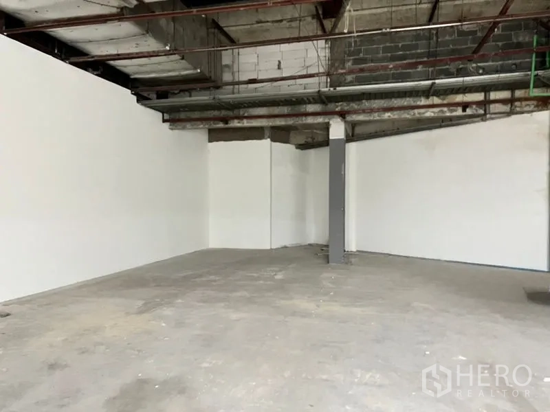 Retail Space for rent in Khlong Toei, Bangkok - Large retail area with white perimeter walls, a central column, and an exposed ceiling.