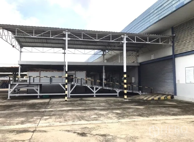 Factory for rent in Bang Bua Thong, Nonthaburi - Covered loading docks with ramps and roller shutter doors.