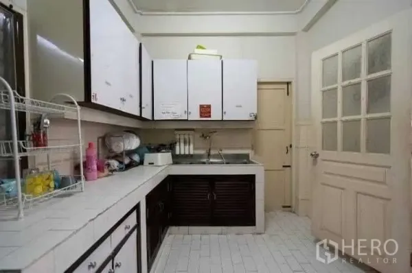 Detached House for rent in Khlong Toei, Bangkok - Functional kitchen with white tiled countertops, upper cabinets, and a stainless-steel sink.