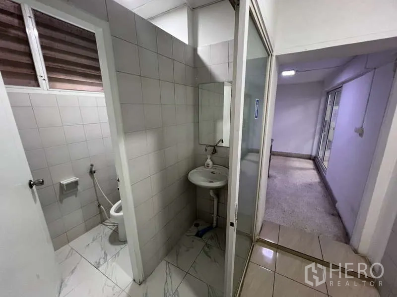 Shophouse for rent or sale in Khlong Toei, Bangkok - Tiled washroom corridor with separate cubicles and sink.