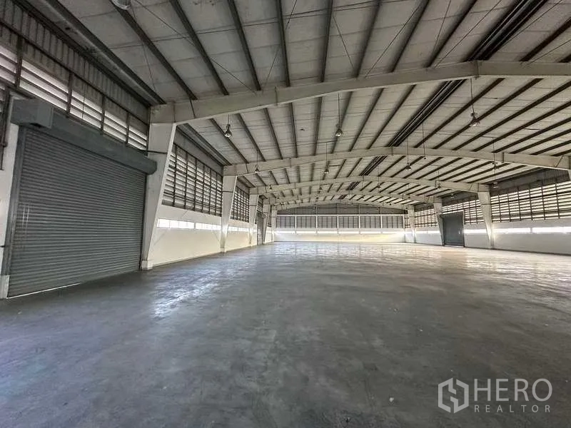 Factory for rent in Khlong Luang, Pathum Thani - Warehouse bay with multiple roller shutter doors and ample maneuvering space for forklifts.
