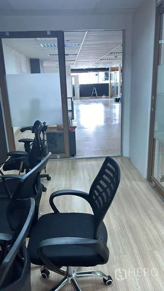 Office Space for rent - Small meeting room with office chairs and a glass partition looking into the main floor.