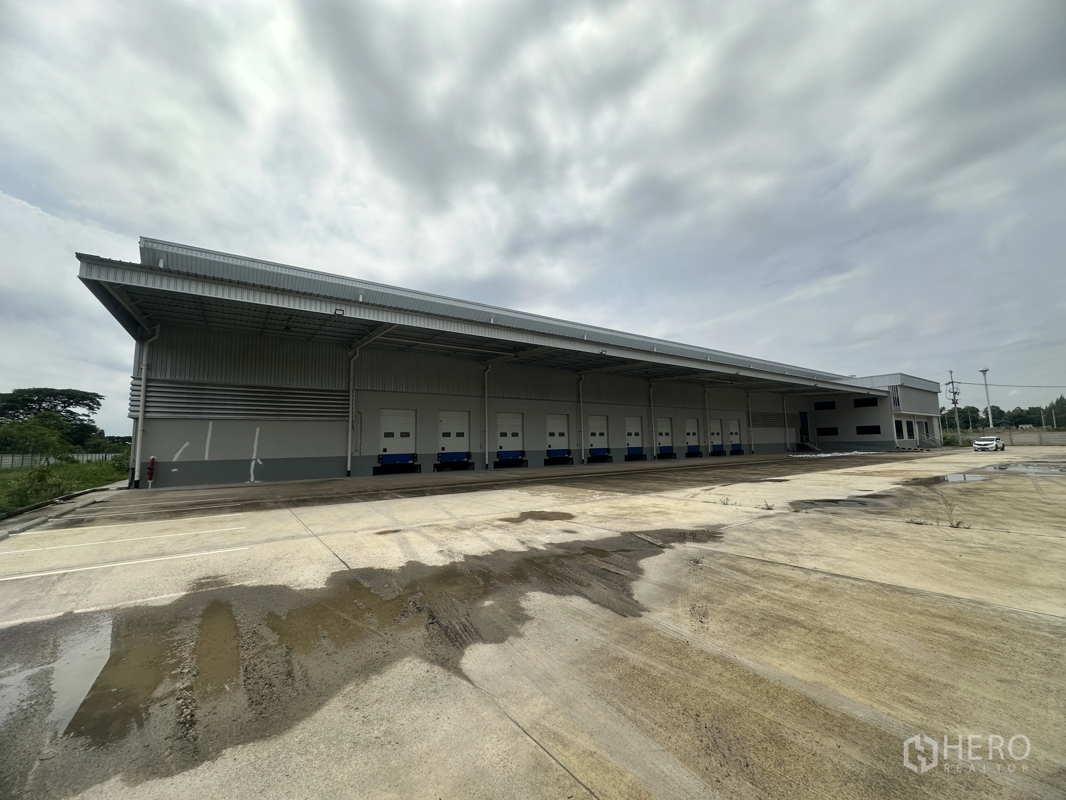 Warehouse for rent in Mueang Chon Buri, Chon Buri - Long exterior facade showing multiple loading bays and a wide concrete yard.