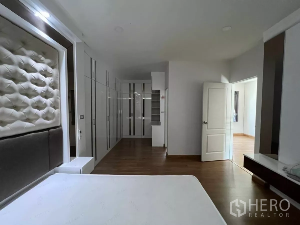 Detached House for rent in Samut Prakan - Master suite view with bed, extensive wardrobes and a doorway to an adjacent room.