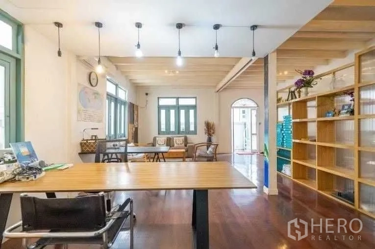 Detached House for rent in Khlong Toei, Bangkok - Bright workspace and lounge with pendant lighting, shelving, and polished wood flooring.