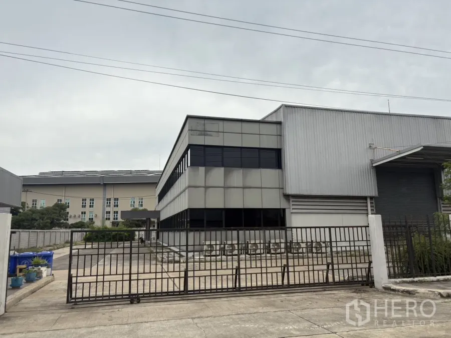 工厂 出租或出售在Samut Prakan - 金属大门入口，可见办公楼和厂房立面。