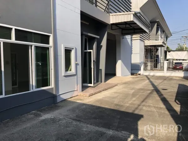 Factory for rent in Lam Luk Ka, Pathum Thani - Front driveway showing glass‑door office entrance beside the covered loading bay.