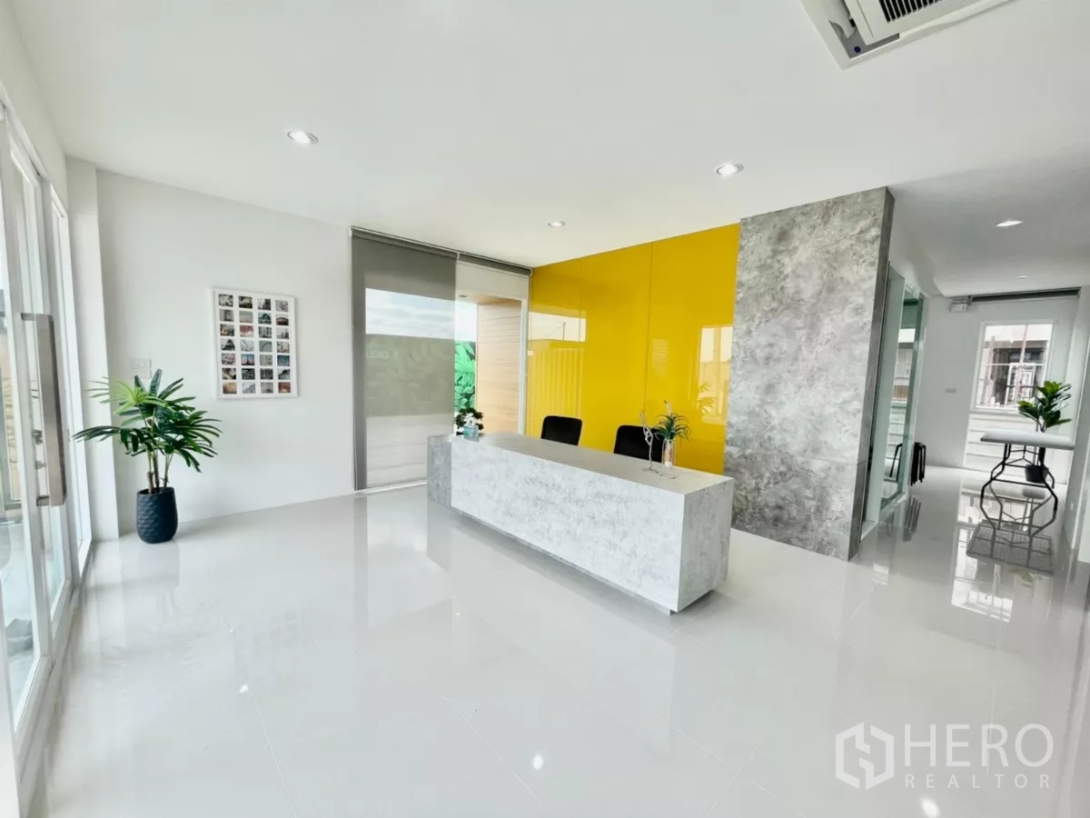 Warehouse for sale in Lam Luk Ka, Pathum Thani - Reception lobby with yellow feature wall, large windows and a marble-look desk.