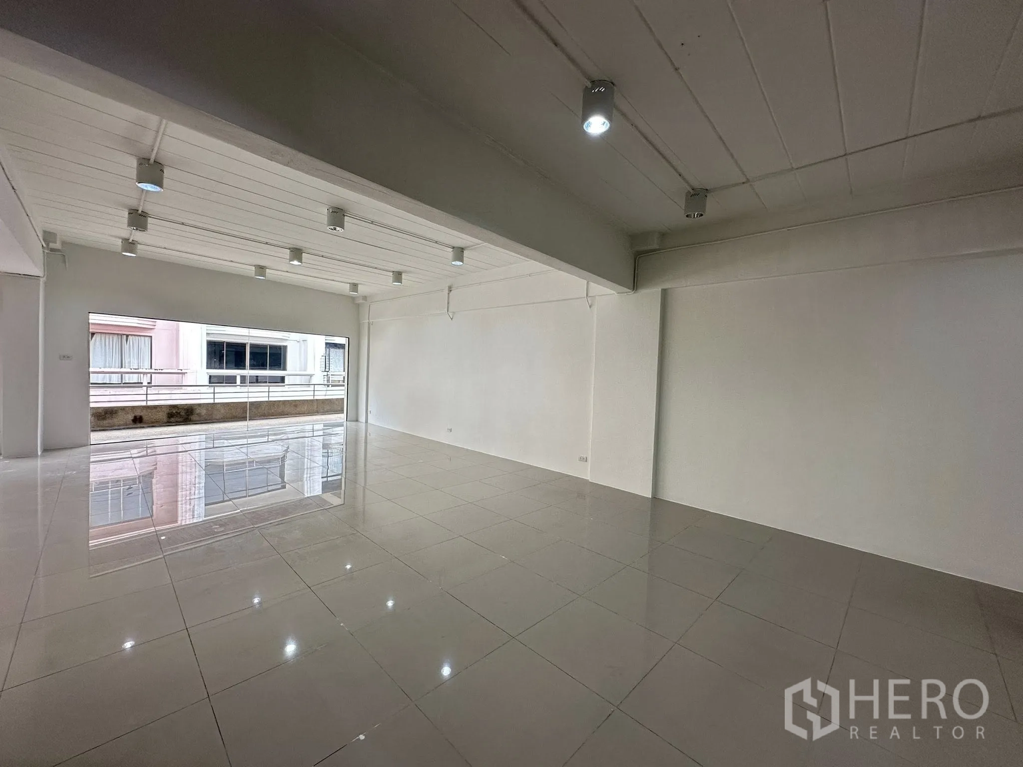 Office Space for rent in Watthana, Bangkok - Open-plan area with beam and spotlights facing a wide picture window.