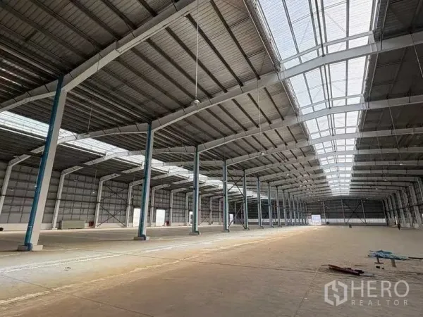 Factory for rent in Rayong - Vast warehouse interior with high steel roof, skylight panels and open production floor.
