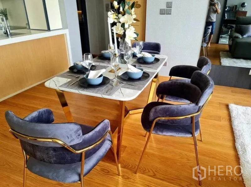 Condominium for rent in Khlong Toei, Bangkok - Marble-top dining table set with velvet chairs and elegant tableware.