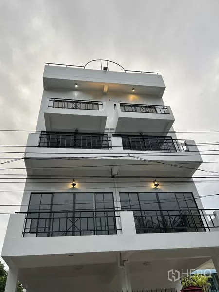 Home Office for rent or sale in Phra Khanong, Bangkok - Multi-storey white home office facade with balconies and black-framed windows at dusk.