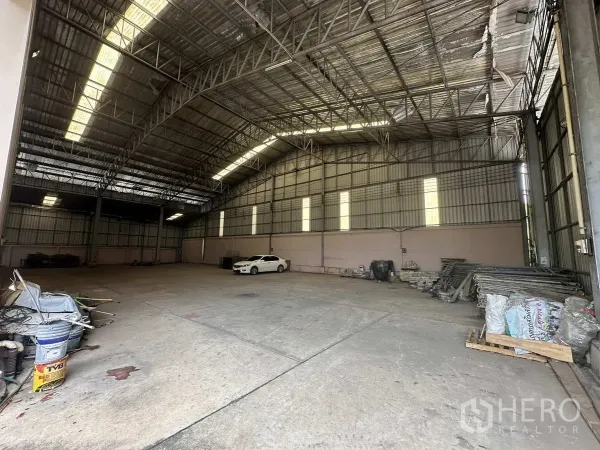 Factory for rent in Pathum Thani - Spacious warehouse interior with a high steel-truss roof, skylights and clear-span concrete floor.