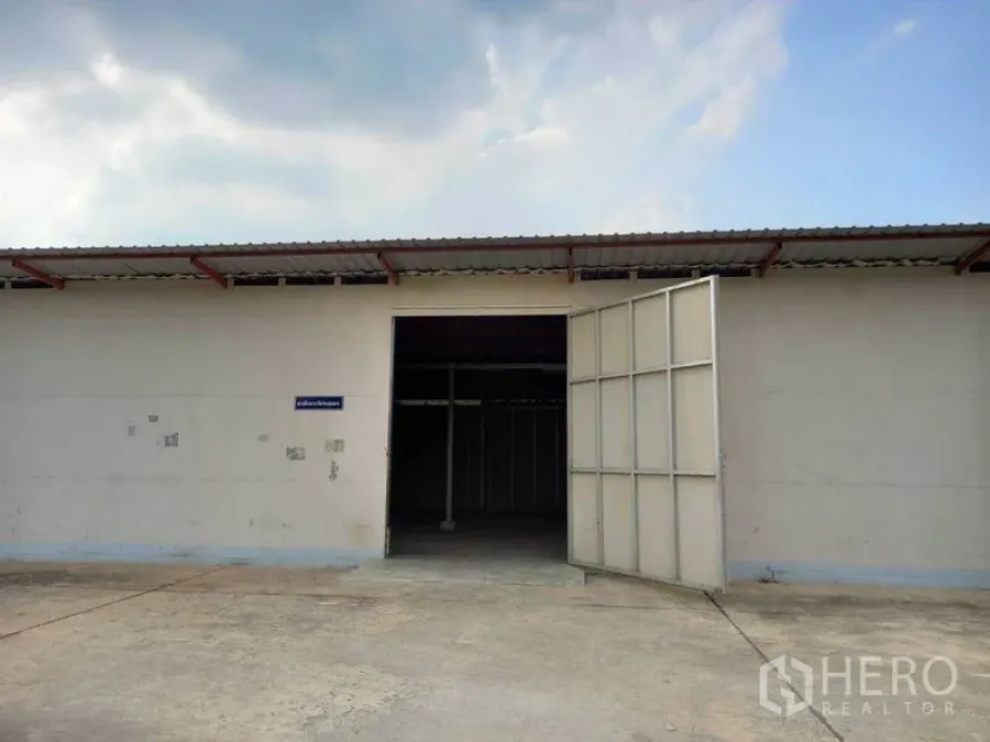 货栈 出租在Pathum Thani - 仓库外立面，金属推拉大门与宽阔混凝土场地（巴吞他尼市区）