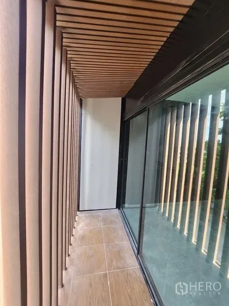 Warehouse for rent in Lam Luk Ka, Pathum Thani - Narrow shaded balcony with timber slats beside a glass wall.
