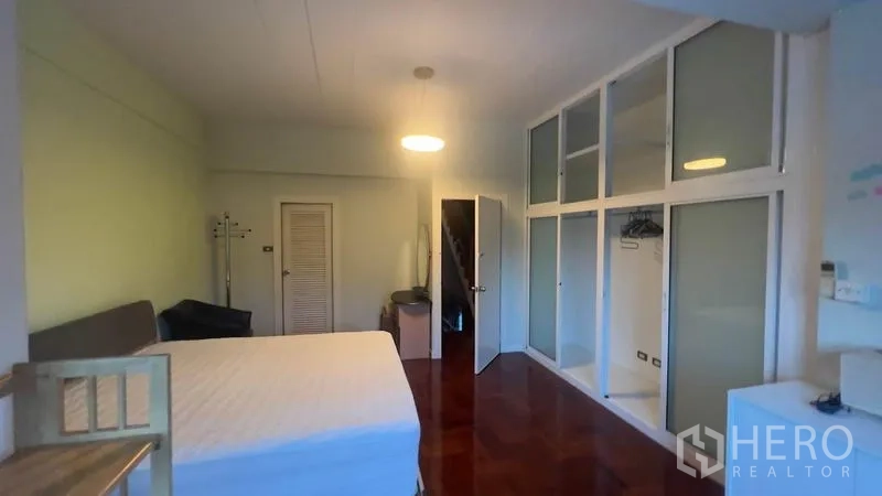 Townhouse for rent or sale in Khlong Toei, Bangkok - Bedroom with built-in wardrobes and glossy wooden flooring.