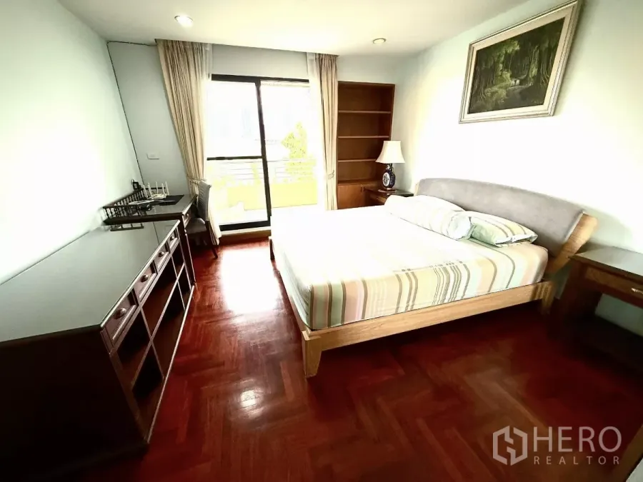Condominium for rent in Sathon, Bangkok - Primary bedroom with queen bed, desk, built‑in shelves and balcony door.