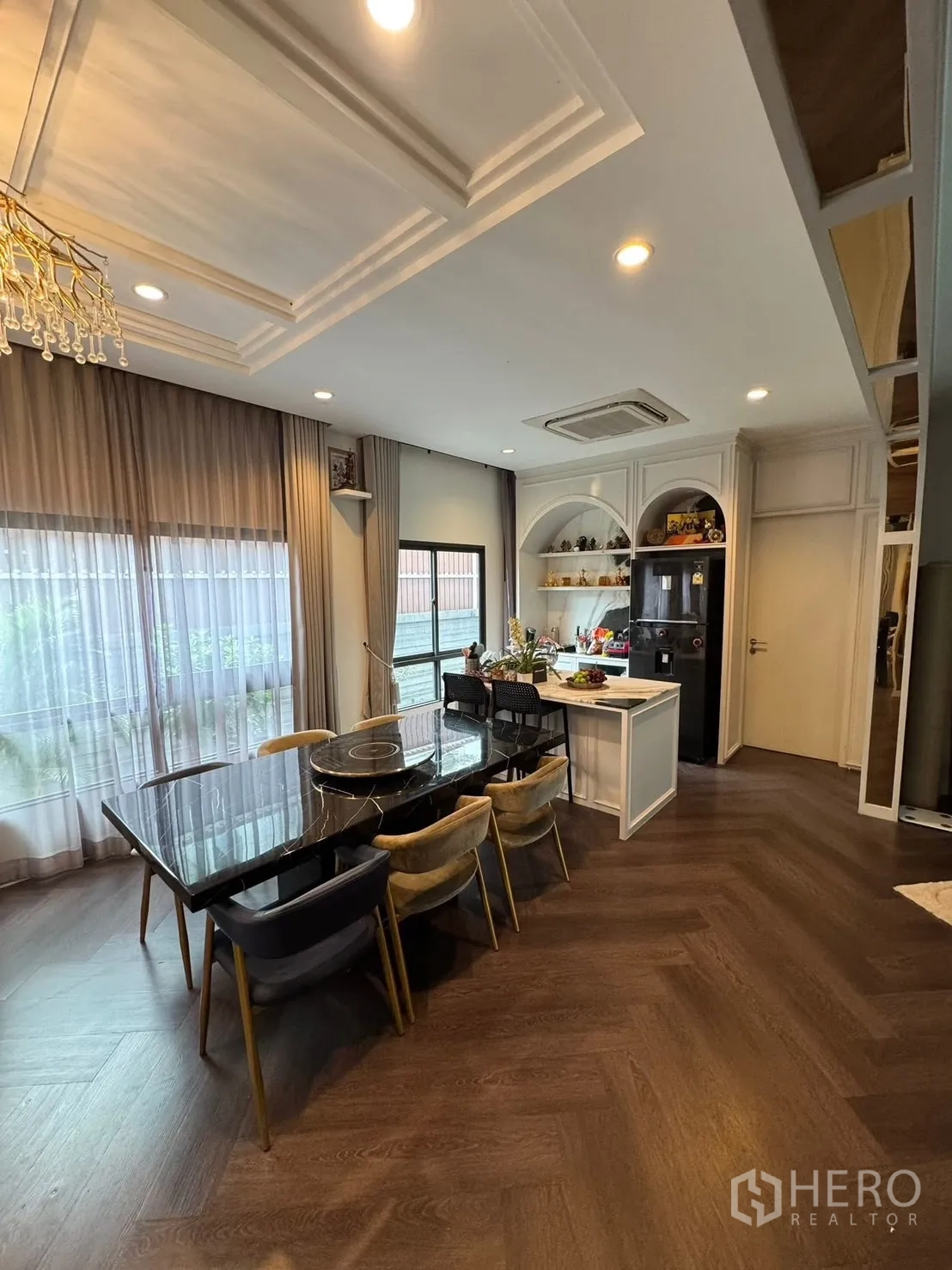 Detached House for sale in Mueang Pathum Thani, Pathum Thani - Dining room with black marble table, six chairs and kitchen island.