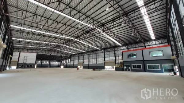 Factory for rent or sale in Phanat Nikhom, Chon Buri - Clear-span warehouse interior with steel truss roof and attached two-storey office.