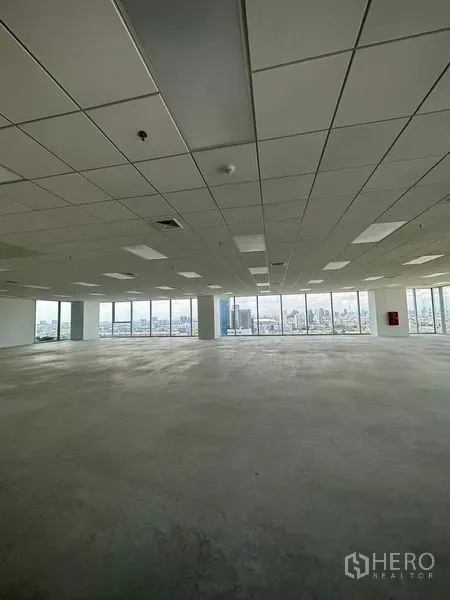 Office Space for rent in Bang Na, Bangkok - Large unfurnished office area featuring suspended ceiling panels, concrete floor, and expansive windows overlooking the city.
