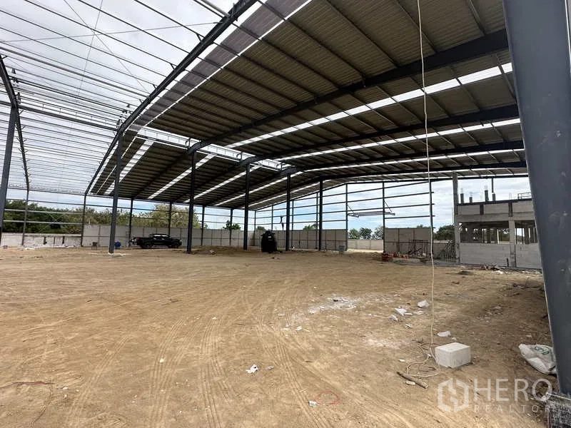 Warehouse for rent or sale in Nikhom Phatthana, Rayong - Spacious warehouse interior with roof panels fitted on one side and ample loading area.