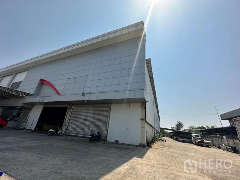 Warehouse for rent in Lam Luk Ka, Pathum Thani - Side view of the warehouse corner with a large roller door and open service yard.