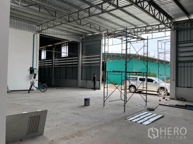 Warehouse for rent in Mueang Pathum Thani, Pathum Thani - Covered loading bay with tall sliding doors and vehicle access suitable for trucks and forklifts.