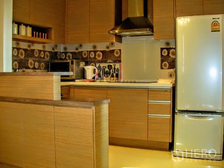 Condominium for rent in Khlong Toei, Bangkok - Built-in wooden kitchen with backsplash, cooktop and hood, microwave and full-size refrigerator.