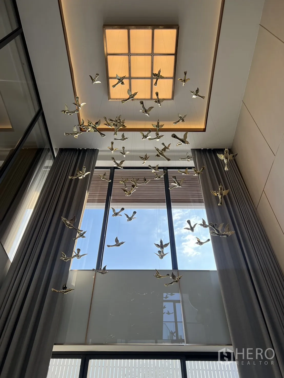 Detached House for sale in Lat Phrao, Bangkok - Lofty ceiling view with skylight and suspended golden bird sculptures.