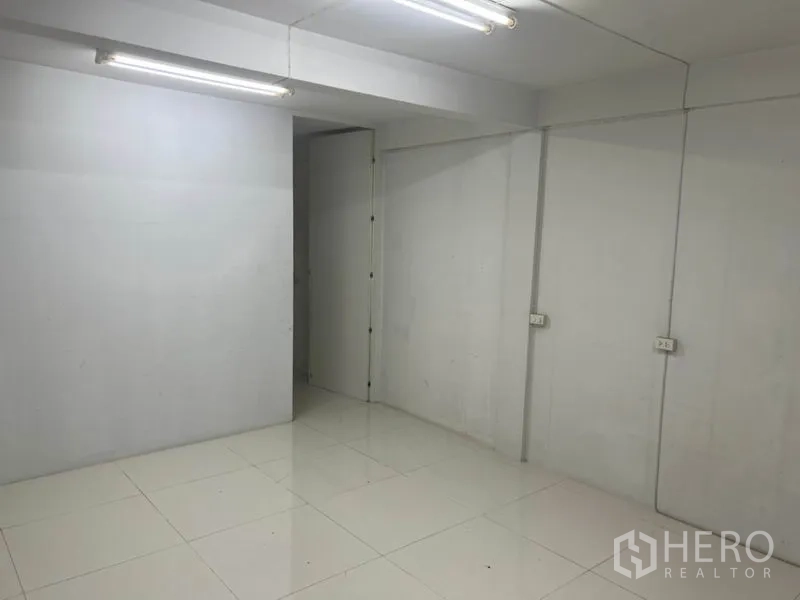 Shophouse for rent in Bang Rak, Bangkok - Simple multipurpose room with white walls, fluorescent lights and an interior door.
