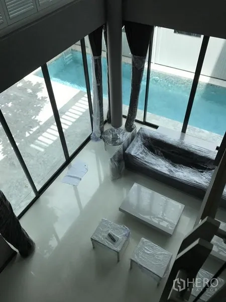 Detached House for rent in Bang Kapi, Bangkok - Double-height living room with floor-to-ceiling windows overlooking a private lap pool.