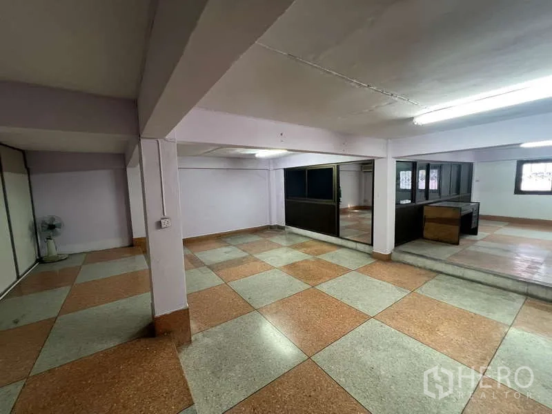 Shophouse for rent in Suan Luang, Bangkok - Spacious upper floor with checker tiles, partitioned offices and fluorescent lighting.