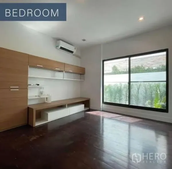 Detached House for sale in Khlong Toei, Bangkok - Bright bedroom with wood floors, built-in cabinets and a large garden-facing window.