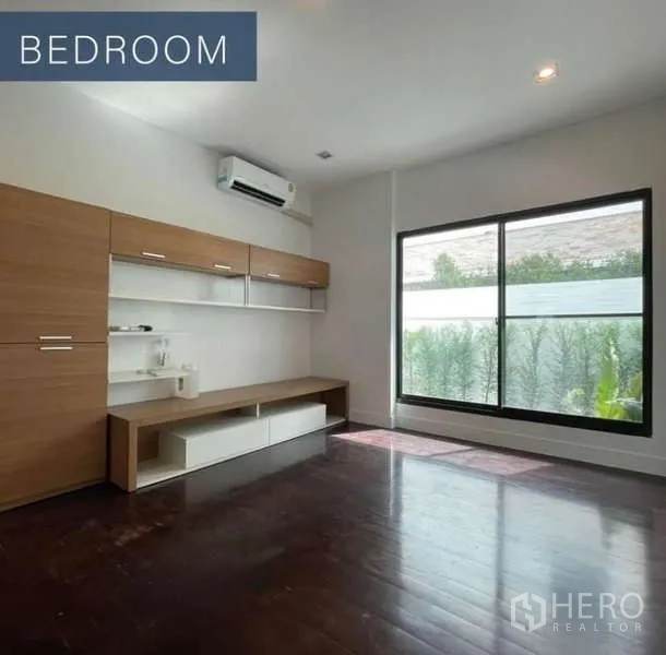 Detached House for sale in Khlong Toei, Bangkok - Bright bedroom with wood floors, built-in cabinets and a large garden-facing window.