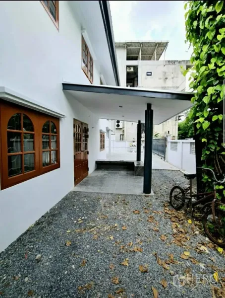 Home Office for rent in Lat Phrao, Bangkok - Front porch with canopy roof, gravel yard and bench beside wooden double doors.