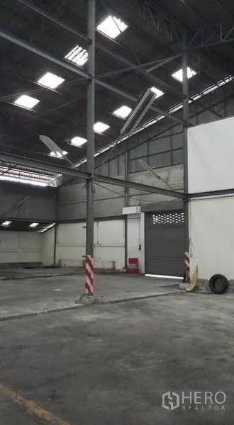 Warehouse for rent in Bang Phli, Samut Prakan - Spacious interior with steel columns, high roof, skylights and a roller door.