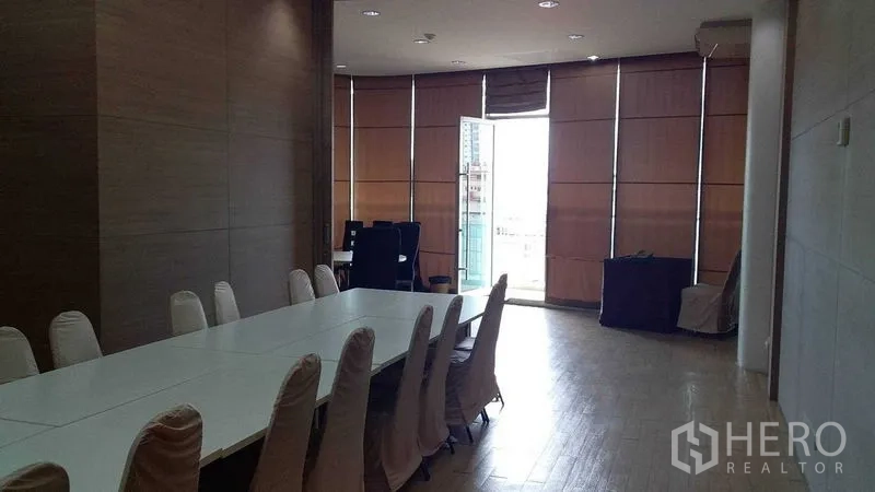 Office Space for rent in Phra Khanong, Bangkok - Conference room with a long white table, slipcovered chairs, wood flooring, and tall blinds.