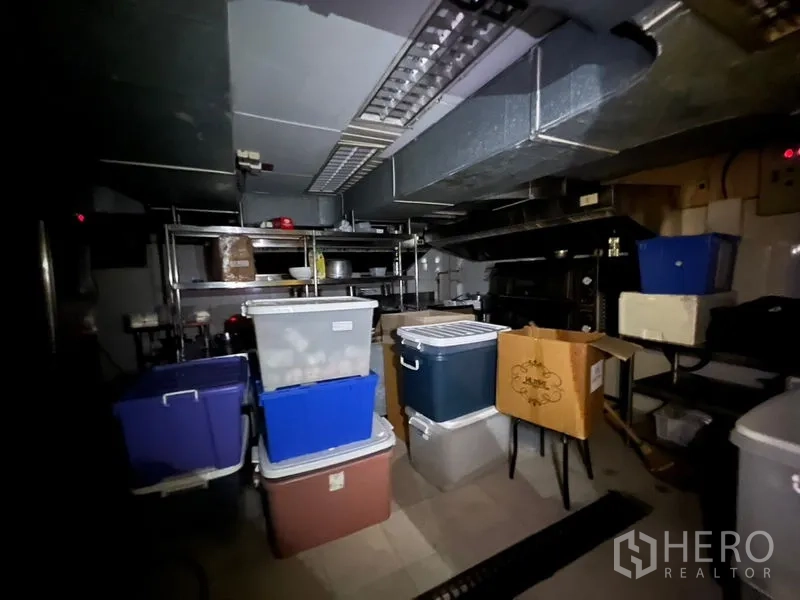 Retail Space for rent or sale in Khlong Toei, Bangkok - Dark back-of-house storage or kitchen with ventilation ducts and plastic containers.
