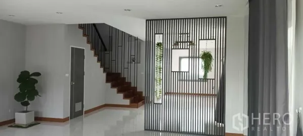 Townhouse for rent or sale in Saphan Sung, Bangkok - Bright open-plan living area with steel slat divider and a wooden staircase.